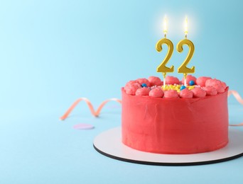 Image of Yummy cake with burning number shaped candles on light blue background, space for text. 22th birthday or other special occasion