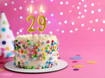 Image of Yummy cake with burning number shaped candles on pink background with blurred lights, space for text. 29th birthday or other special occasion