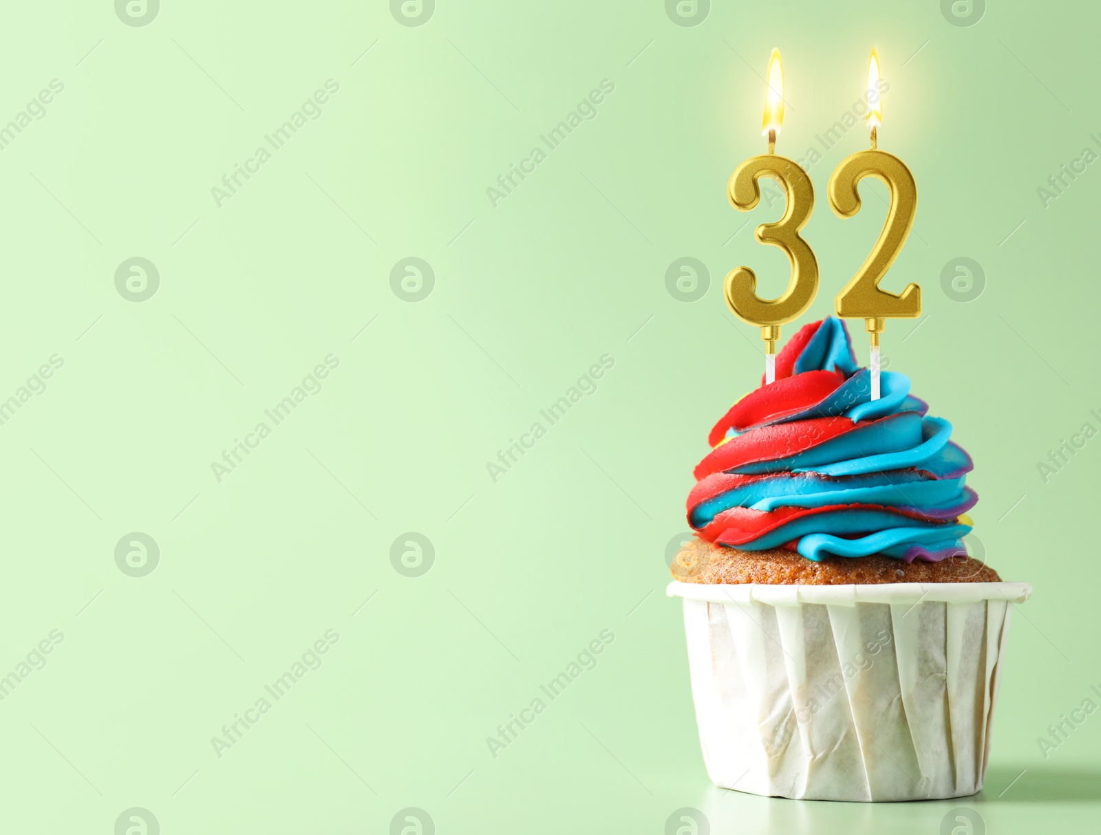 Yummy cupcake with burning number shaped candles on light turquoise background, space for text. 32th birthday or other special occasion Image of Yummy cupcake with burning number shaped candles on light turquoise background, space for text. 32th birthday or other special occasion