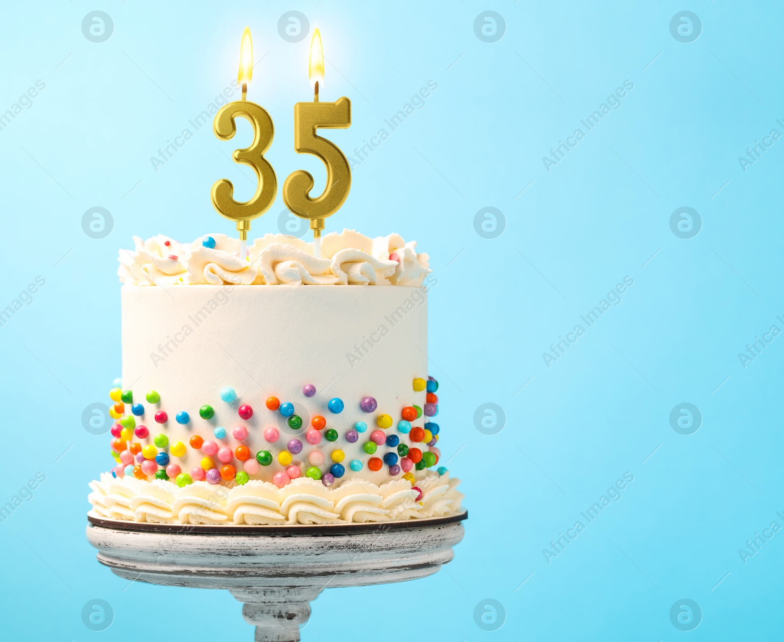 Yummy cake with sprinkles and burning number shaped candles on light blue background, space for text. 35th birthday or other special occasion Image of Yummy cake with sprinkles and burning number shaped candles on light blue background, space for text. 35th birthday or other special occasion