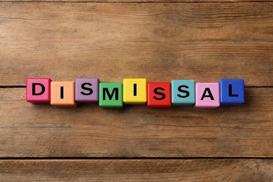 Image of Word Dismissal made of colorful cubes on wooden background, top view