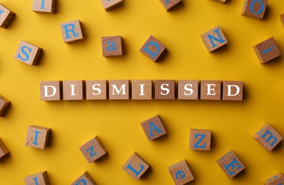 Image of Word Dismissed made of wooden cubes on orange background, top view