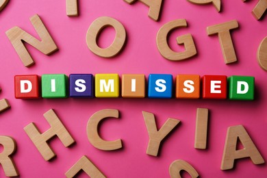 Image of Word Dismissed made of colorful cubes on pink background, top view