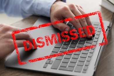 Image of Man using laptop at table and red stamp Dismissed, closeup