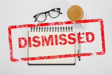Image of Red stamp Dismissed over notebook on white table, top view