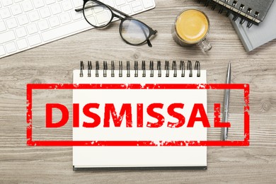 Image of Red stamp Dismissal over notebook on wooden table, top view