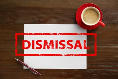 Image of Red stamp Dismissal over wooden table with paper, pen and coffee, top view