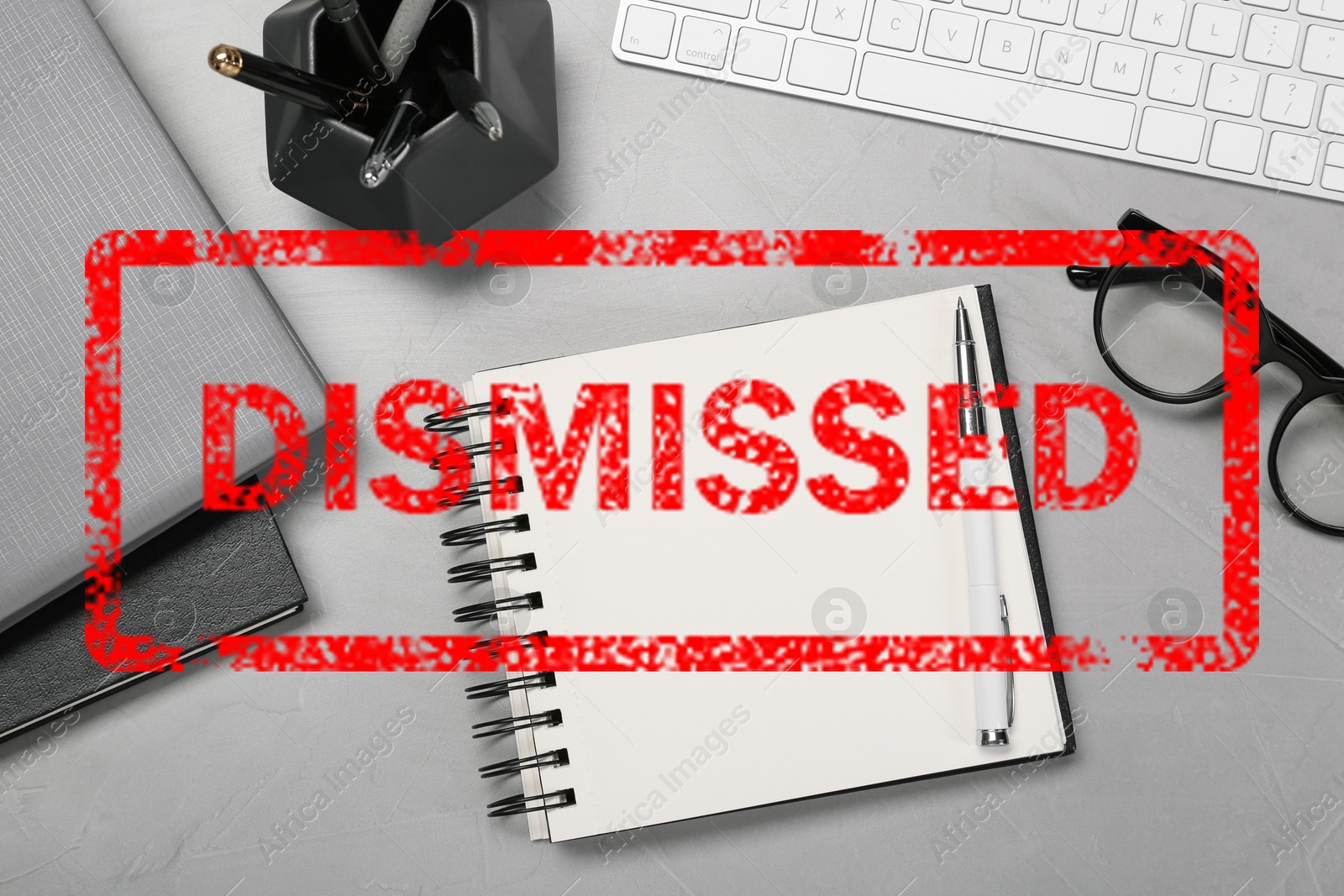 Image of Red stamp Dismissed over office workplace with stationery on table, top view