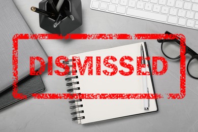 Image of Red stamp Dismissed over office workplace with stationery on table, top view