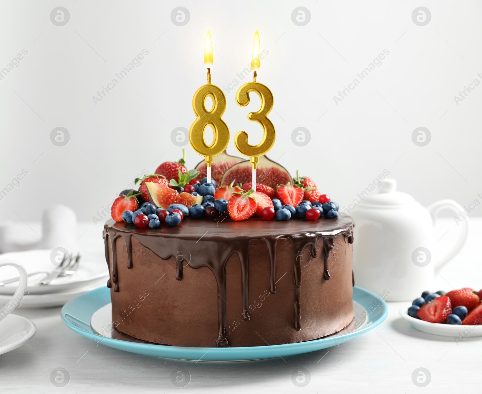 Yummy chocolate cake with fruits and burning number shaped candles on white table. 83th birthday or other special occasion Image of Yummy chocolate cake with fruits and burning number shaped candles on white table. 83th birthday or other special occasion