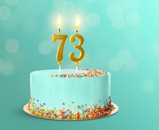 Image of Yummy cake with burning number shaped candles on turquoise background. 73th birthday or other special occasion