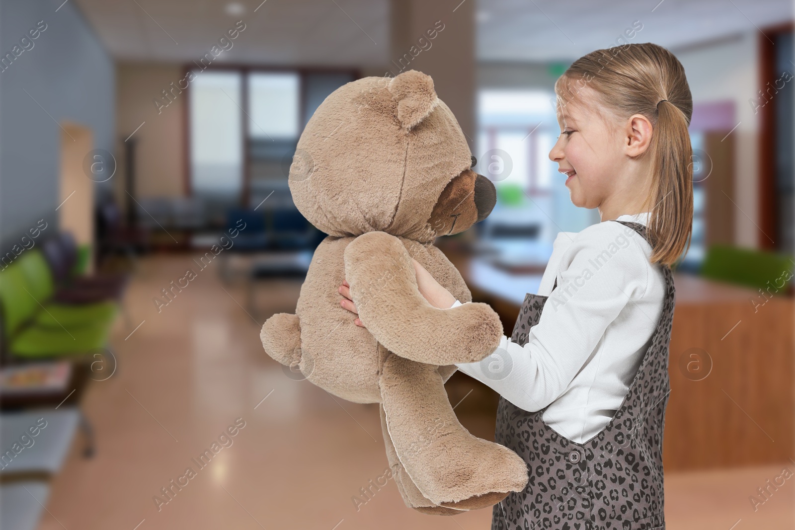 Image of Cute little girl with toy bear in lobby of children's hospital