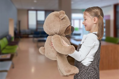 Image of Cute little girl with toy bear in lobby of children's hospital