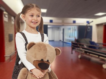 Image of Cute little girl with toy bear in hallway of children's hospital