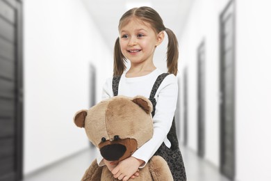 Image of Cute little girl with toy bear in hallway of children's hospital