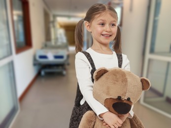 Image of Cute little girl with toy bear in hallway of children's hospital