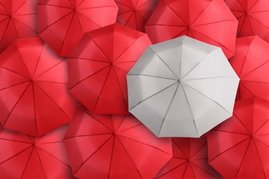 Image of White umbrella among red ones, top view