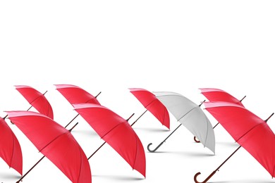 Image of White umbrella among red ones against white background