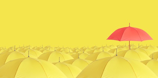 Image of Red umbrella among yellow ones against color background. Banner design