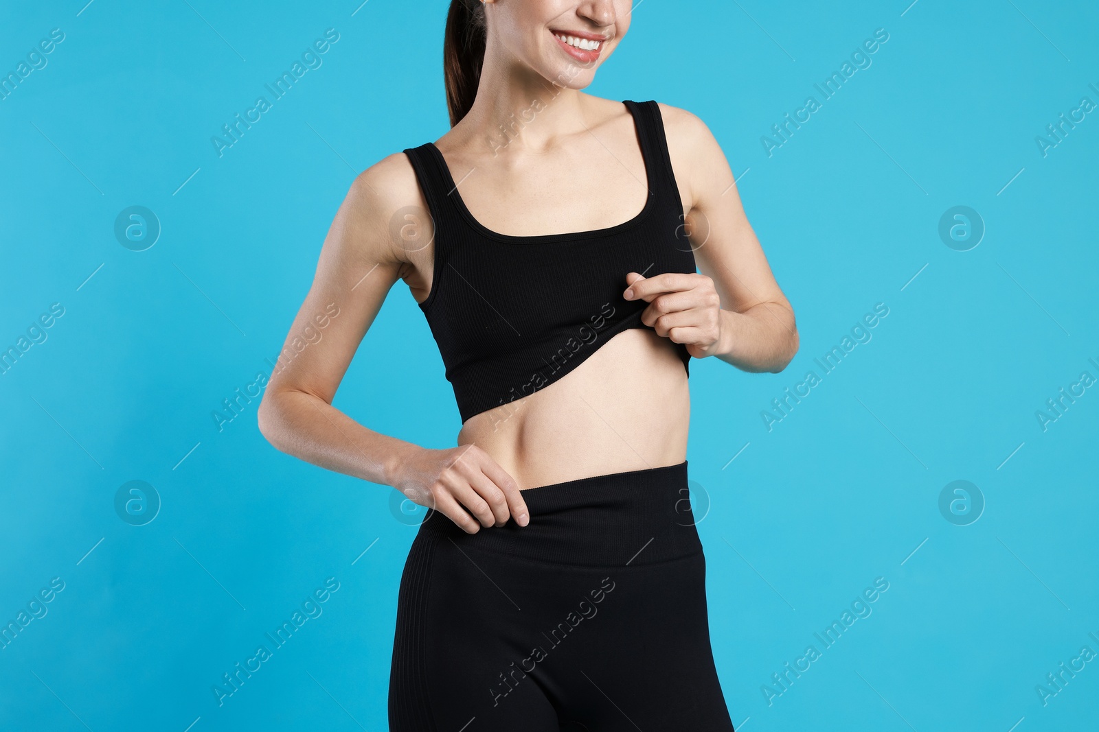 Beautiful woman with flat belly on light blue background, closeup Photo of Beautiful woman with flat belly on light blue background, closeup