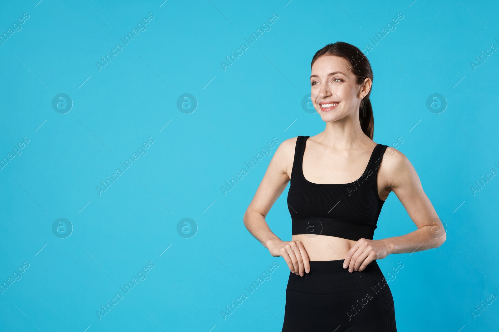 Beautiful woman with flat belly on light blue background, space for text Photo of Beautiful woman with flat belly on light blue background, space for text