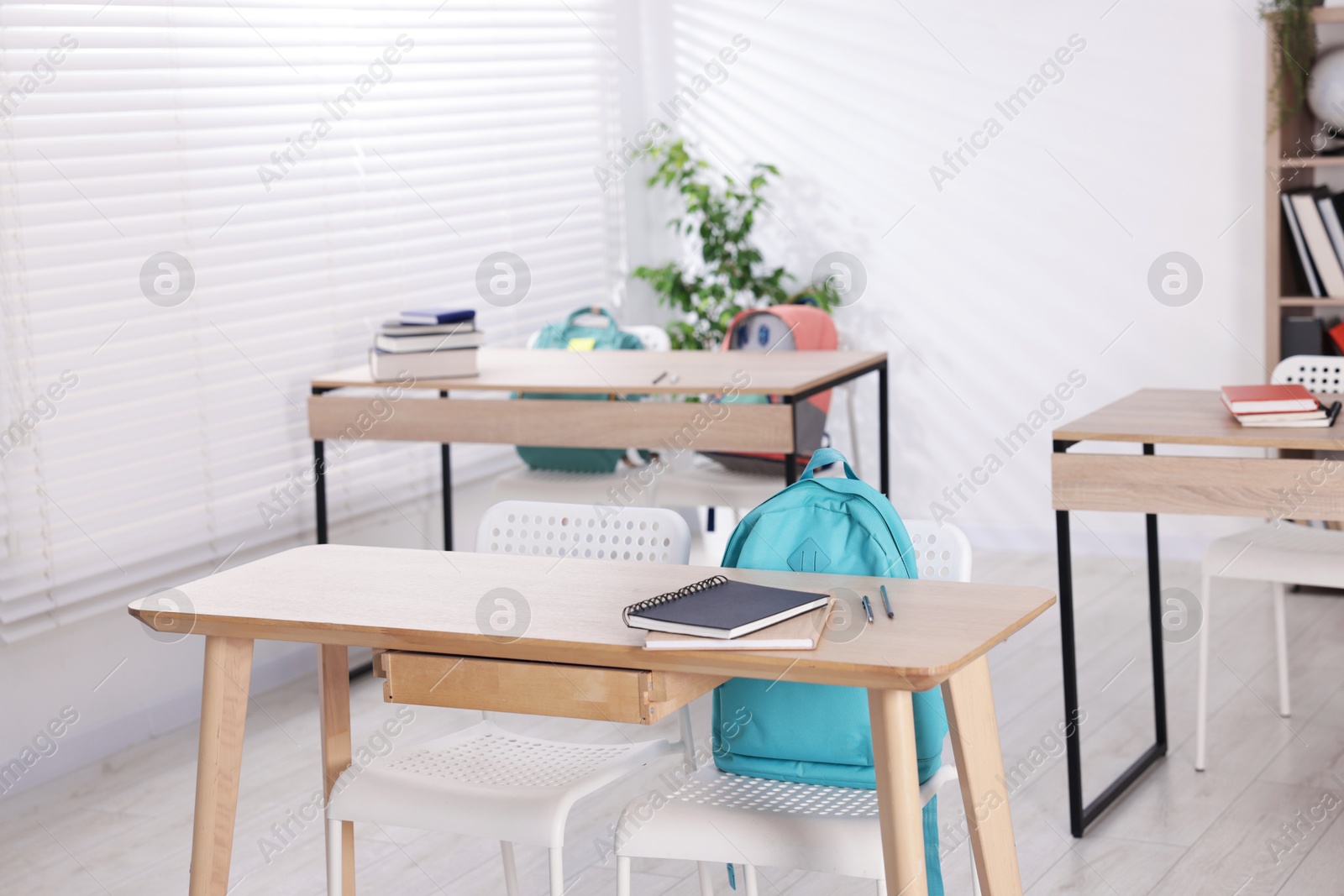Empty classroom with wooden desks, chairs and backpacks Photo of Empty classroom with wooden desks, chairs and backpacks