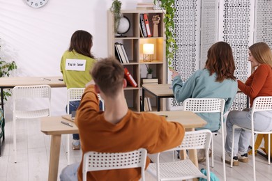 Photo of Schoolmates bullying teenage girl with sign You Loser on her back at school
