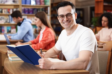 Photo of People studying at desks in public library, selective focus