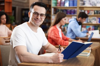Photo of People studying at desks in public library, selective focus