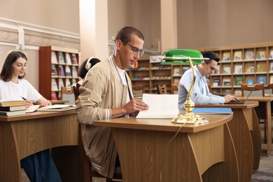 Photo of People studying at desks in public library