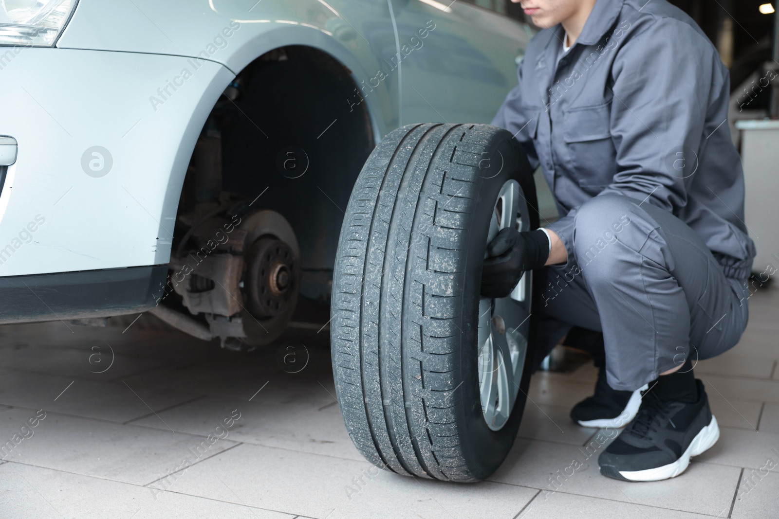 Mechanic changing tire at car service, closeup Photo of Mechanic changing tire at car service, closeup