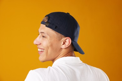 Photo of Young man in stylish baseball hat on orange background