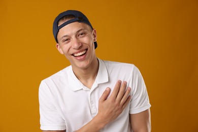 Photo of Young man in stylish baseball hat on orange background