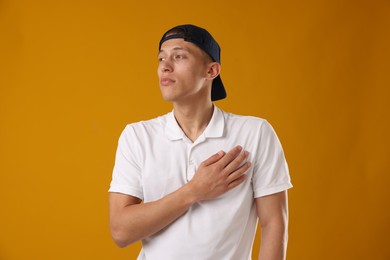 Photo of Young man in stylish baseball hat on orange background