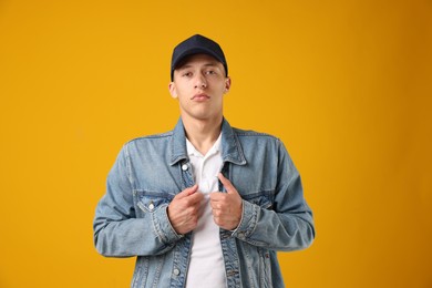 Photo of Young man in stylish baseball hat on orange background