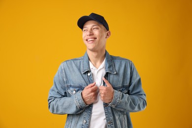 Photo of Young man in stylish baseball hat on orange background