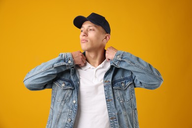 Photo of Young man in stylish baseball hat on orange background