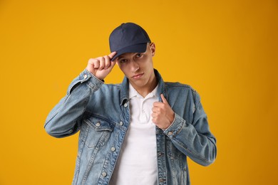 Photo of Young man in stylish baseball hat on orange background