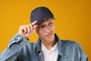 Photo of Young man in stylish baseball hat on orange background