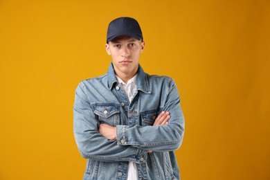 Photo of Young man in stylish baseball hat on orange background