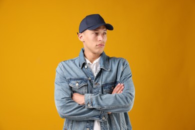 Photo of Young man in stylish baseball hat on orange background