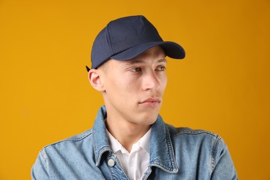 Photo of Young man in stylish baseball hat on orange background