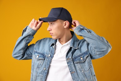 Photo of Young man in stylish baseball hat on orange background