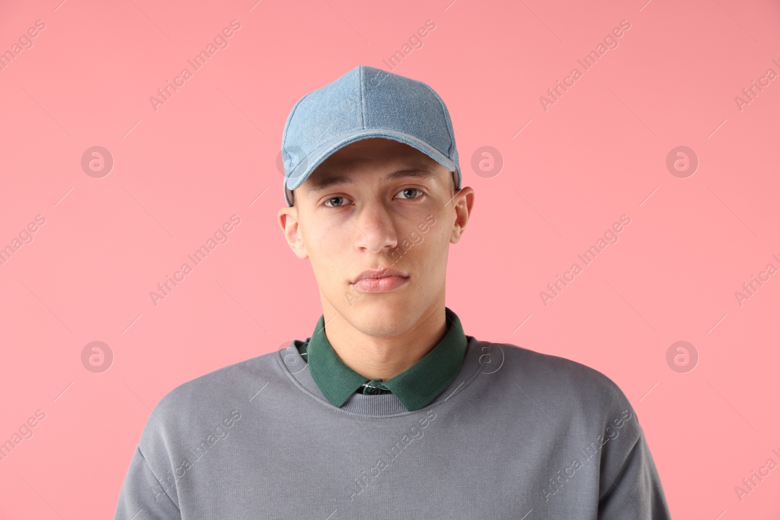 Young man in stylish baseball hat on pink background Photo of Young man in stylish baseball hat on pink background
