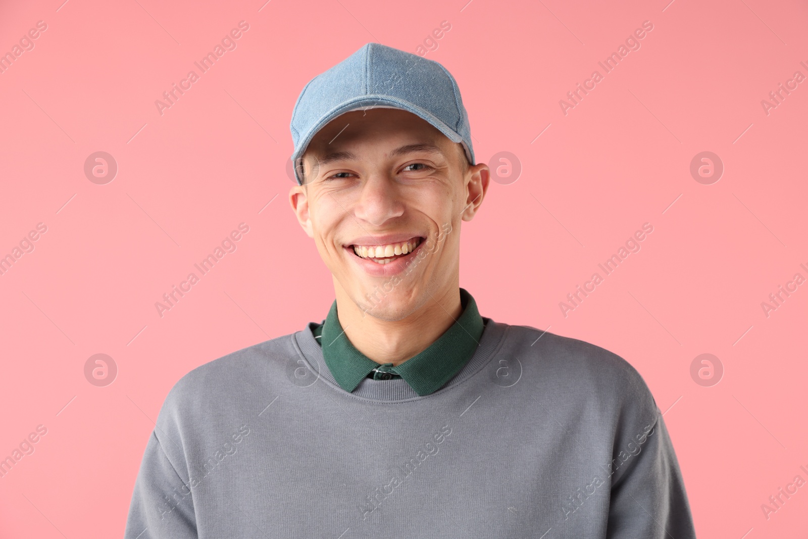 Young man in stylish baseball hat on pink background Photo of Young man in stylish baseball hat on pink background