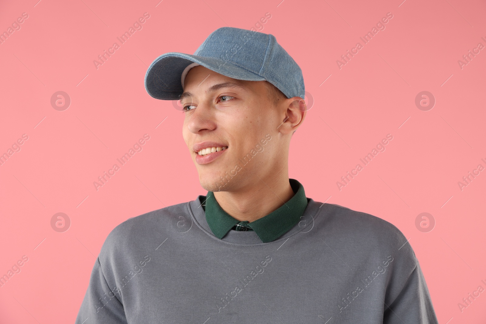 Young man in stylish baseball hat on pink background Photo of Young man in stylish baseball hat on pink background