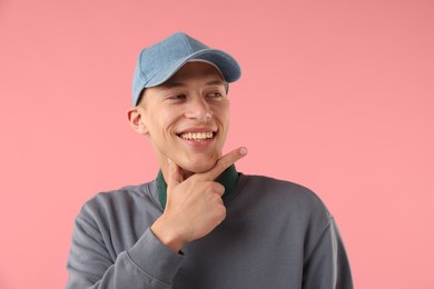 Photo of Young man in stylish baseball hat on pink background