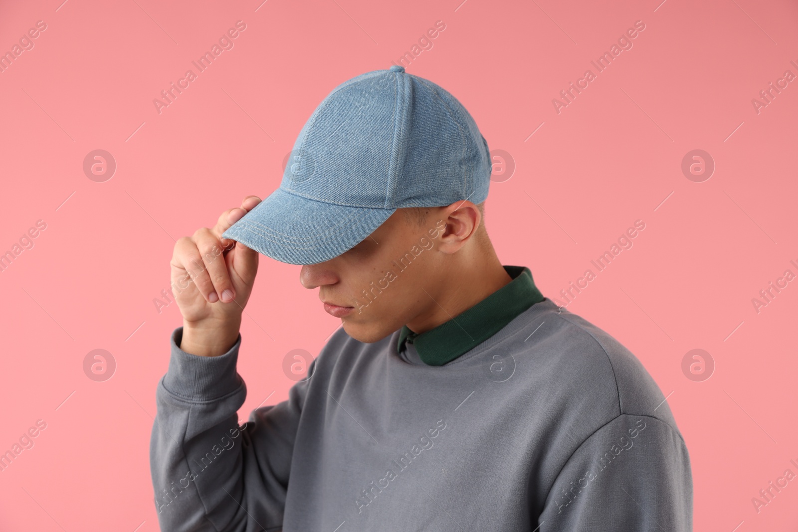 Young man in stylish baseball hat on pink background Photo of Young man in stylish baseball hat on pink background