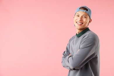 Photo of Young man in stylish baseball hat on pink background, space for text
