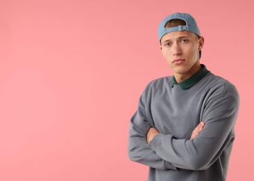 Photo of Young man in stylish baseball hat on pink background, space for text